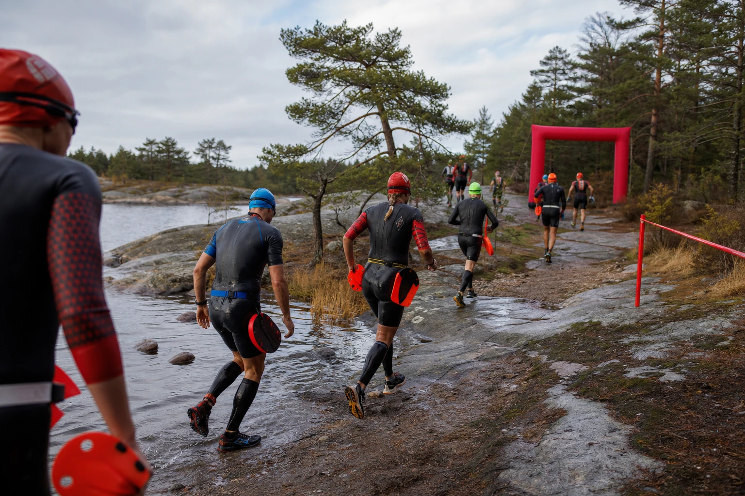 Deltagare i våtdräkt springer längs en klippstrand