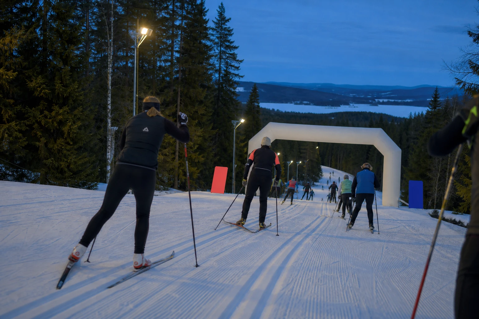 Långt led av längdskidåkare över ett snötäckt fält